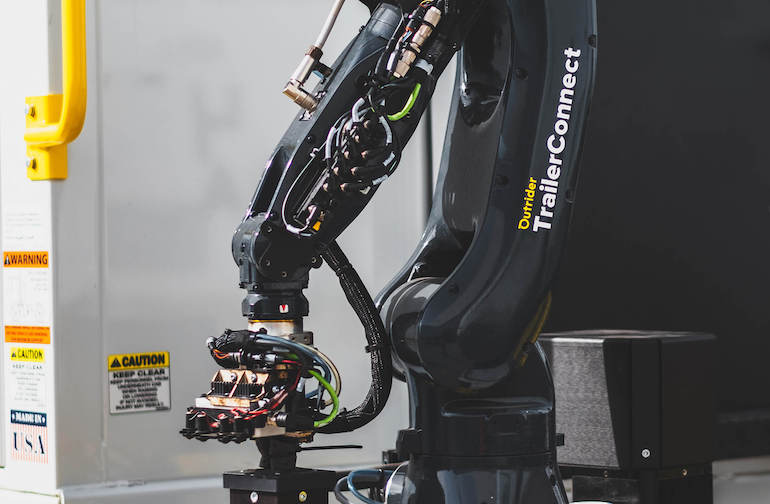 Outrider TrailerConnect uses a robotic arm to connect power and hoses.